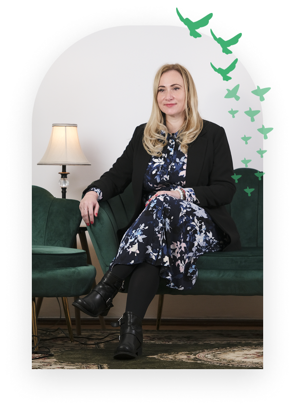 Psihoterapeut Iulia Dolpischi in cabinet pe o canapea verde, cu decor grup pasari in spate